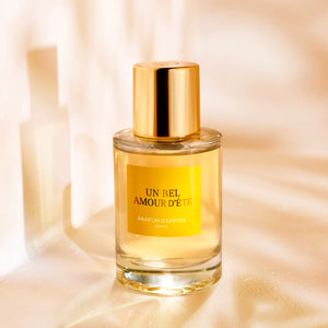 Parfum d'Empire - Un Bel Amour d’Été edler Flakon mit goldfarbenem Verschluss und gelbem Label vor warmem Hintergrund