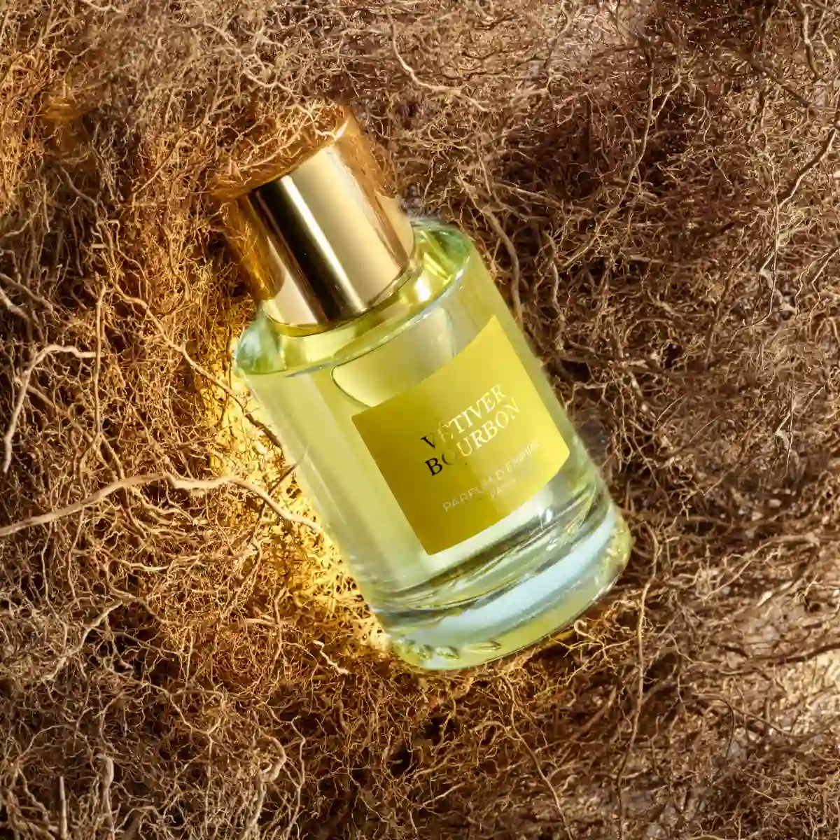 Parfum d'Empire - Vétiver Bourbon Flakon mit goldenem Verschluss eingebettet in natürliche Vetiverwurzeln